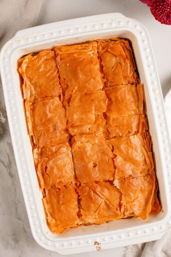 Spanakopita cut into slices in a baking dish.
