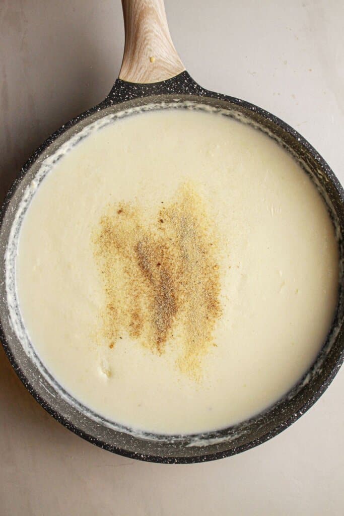 Cream sauce is being made in a large skillet.