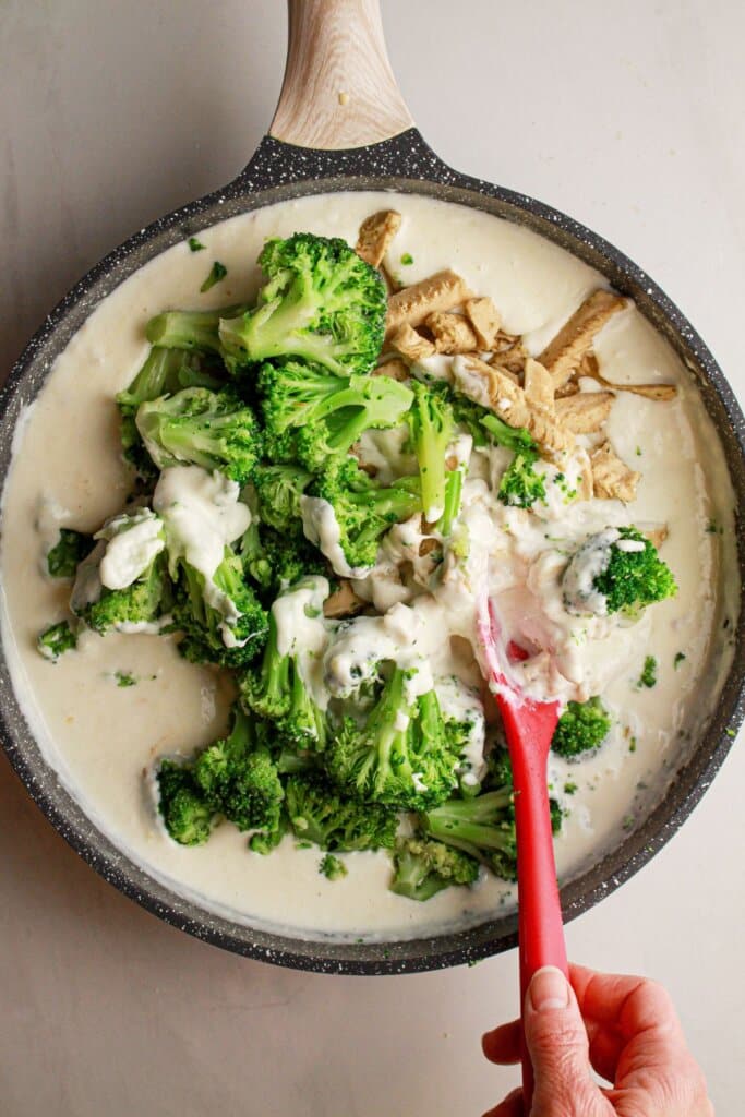 Broccoli and chicken being added to sauce.