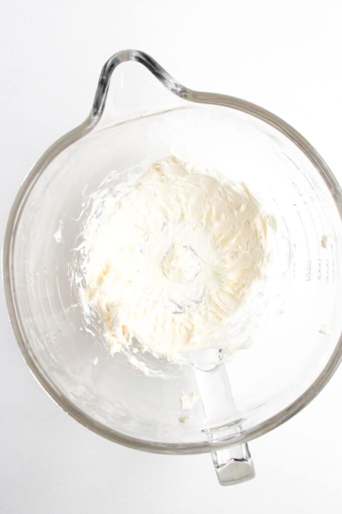 Cream cheese being mixed in a bowl.