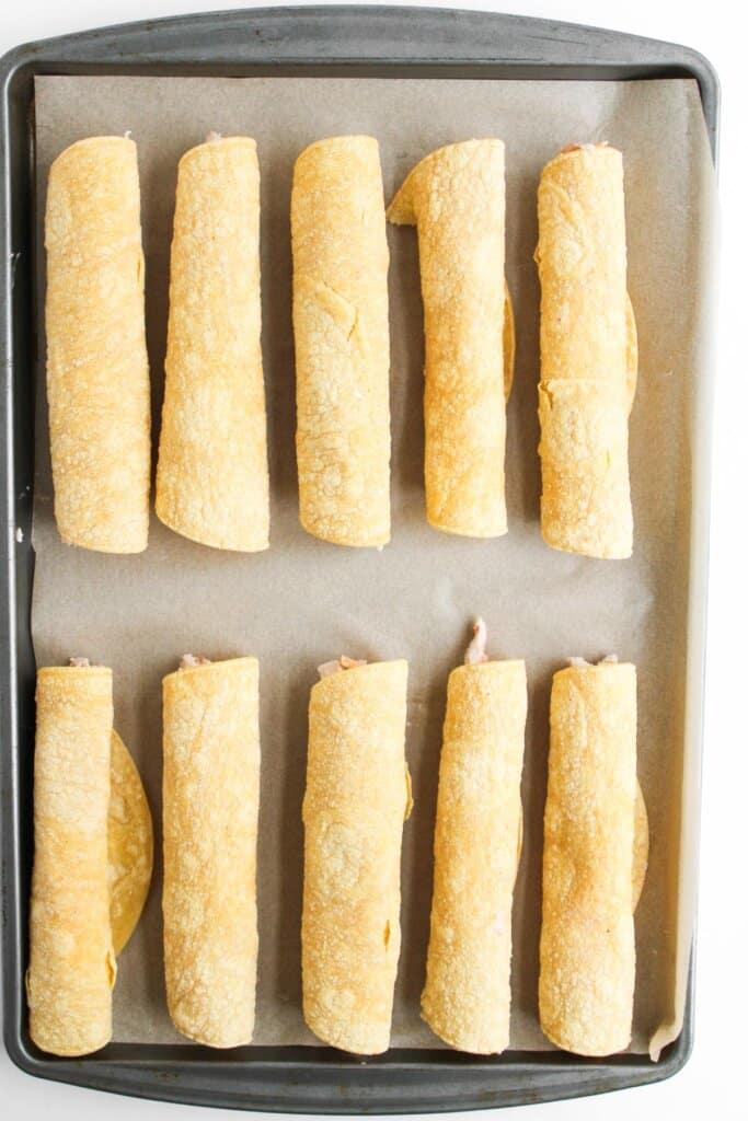 Tortillas rolled up on a baking sheet.