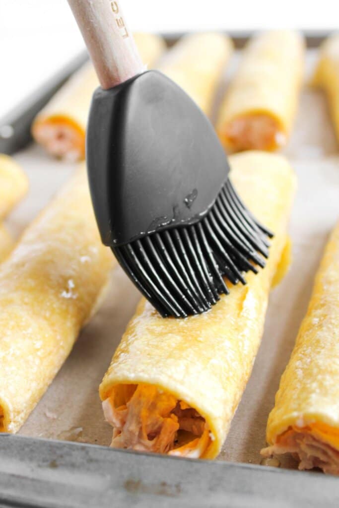 Oil being brushed on top of tortillas.