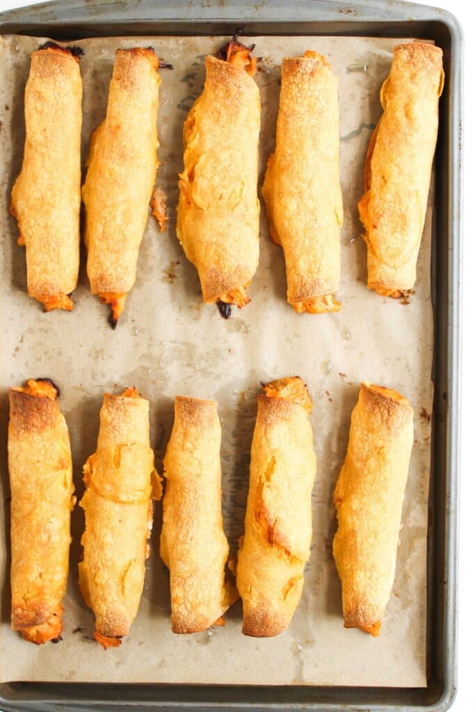 Baked chicken taquitos on a baking sheet.