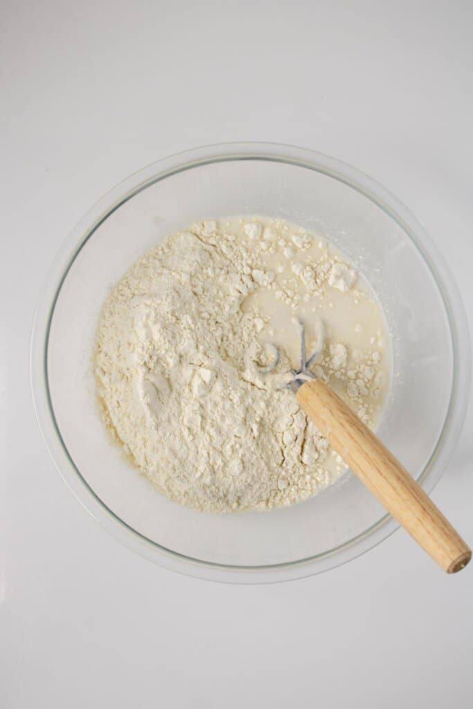 Dough being mixed in a glass bowl.