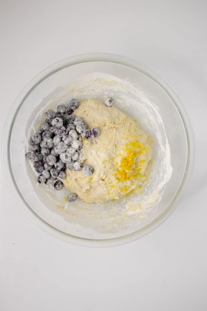 Blueberries and lemon zest being mixed into dough.