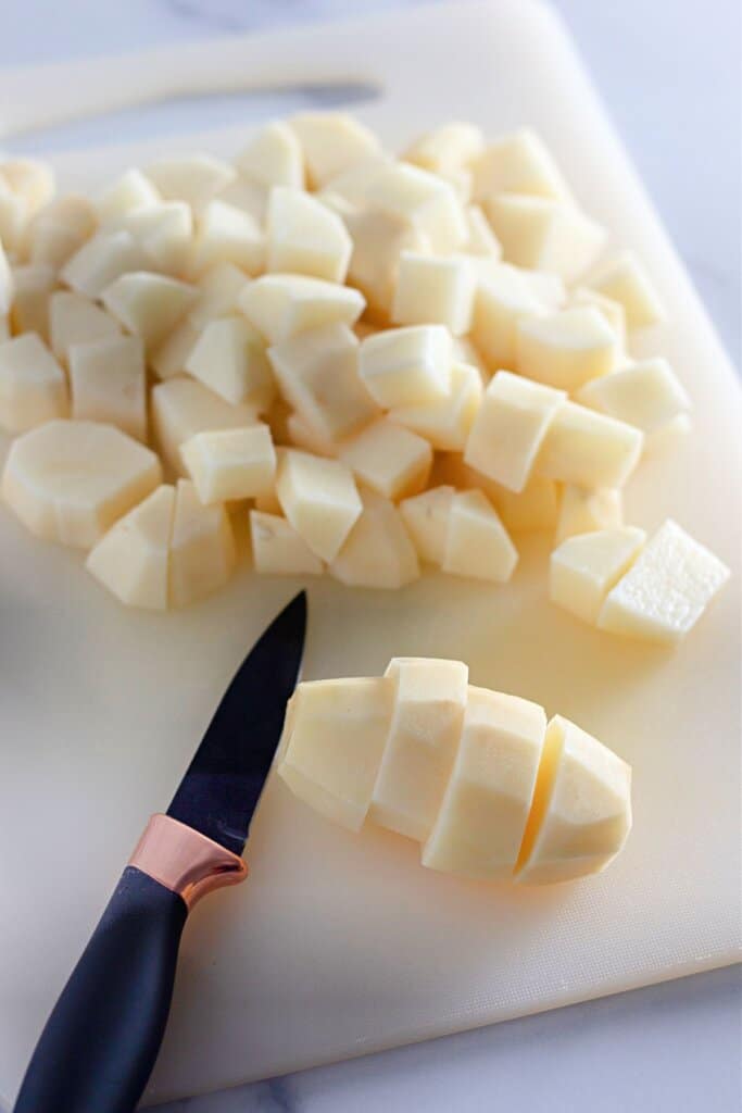 Diced potatoes on a plastic cutting board.