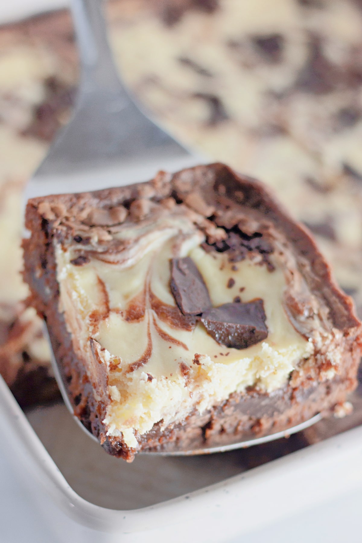 Slice of chocolate cheesecake brownies on a metal spatula.