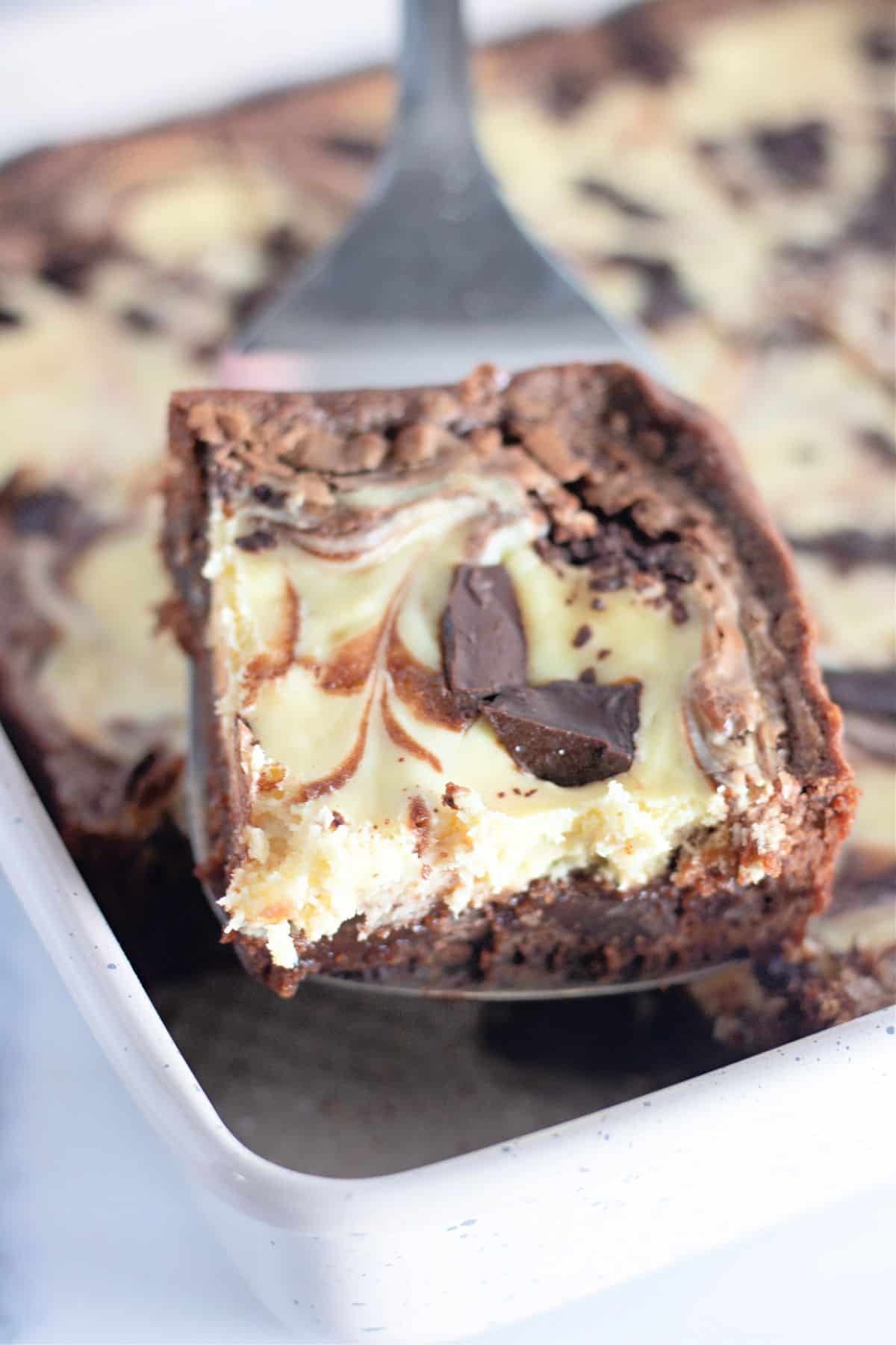 Slice of chocolate cheesecake brownies on a metal spatula.