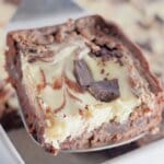 Slice of chocolate cheesecake brownies on a metal spatula.