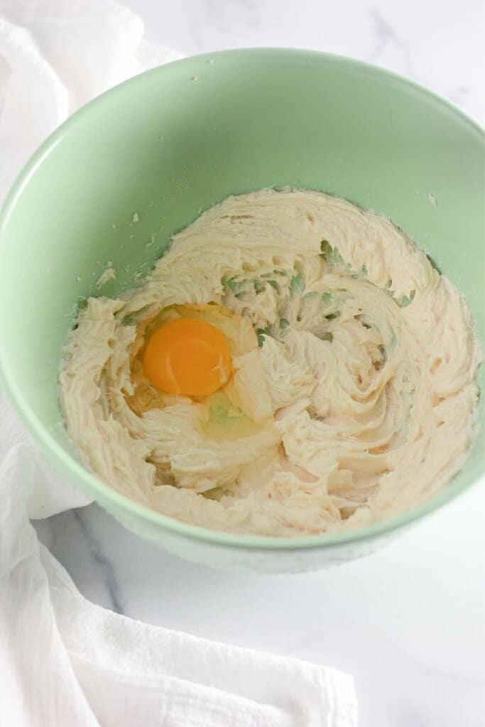 Eggs being added to cream cheese in a bowl.