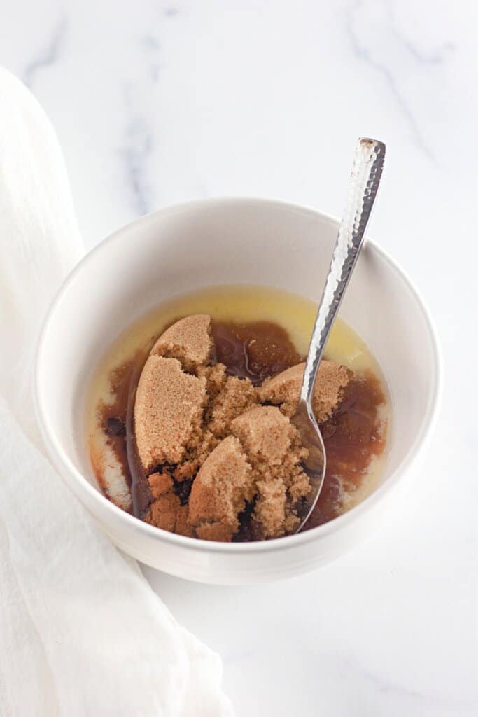 Brown sugar and butter being mixed together in a small bowl.