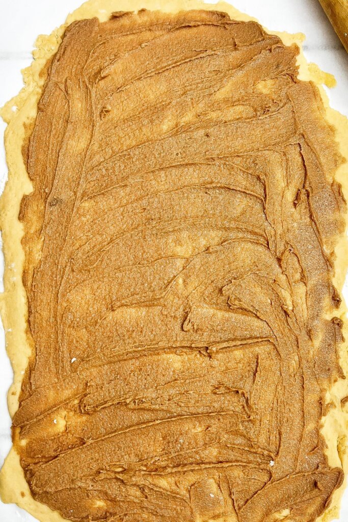 Butter and sugar mixture being spread on dough.