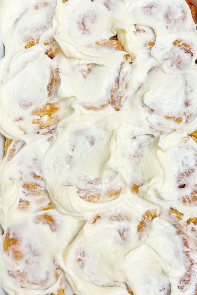 Cinnamon rolls being frosted.