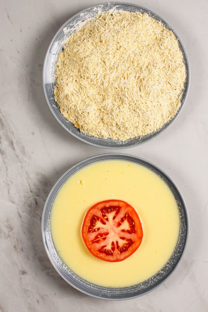Tomato slice being dipped in buttermilk.