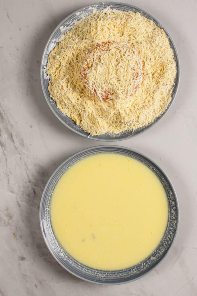 Tomato slice being breaded with cornmeal mixture.