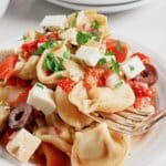 White plate full of greek tortellini pasta salad.