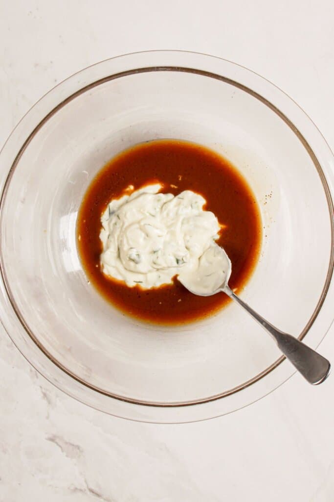 Dressing being mixed in a glass bowl.