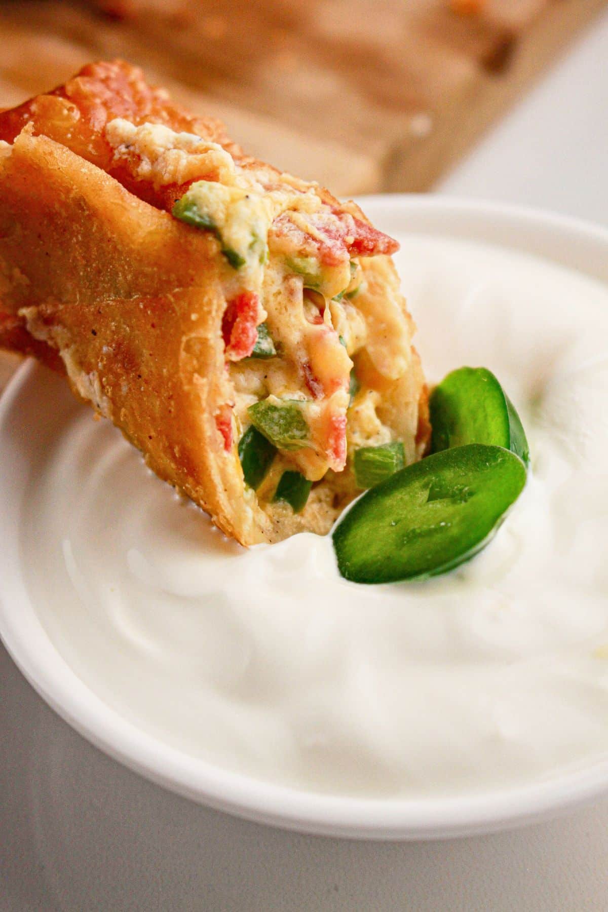 Egg roll being dipped in sour cream.