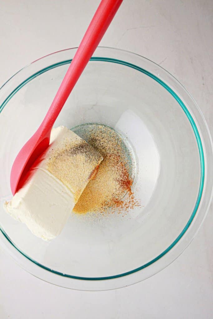 Cream cheese and seasoning in a glass bowl.