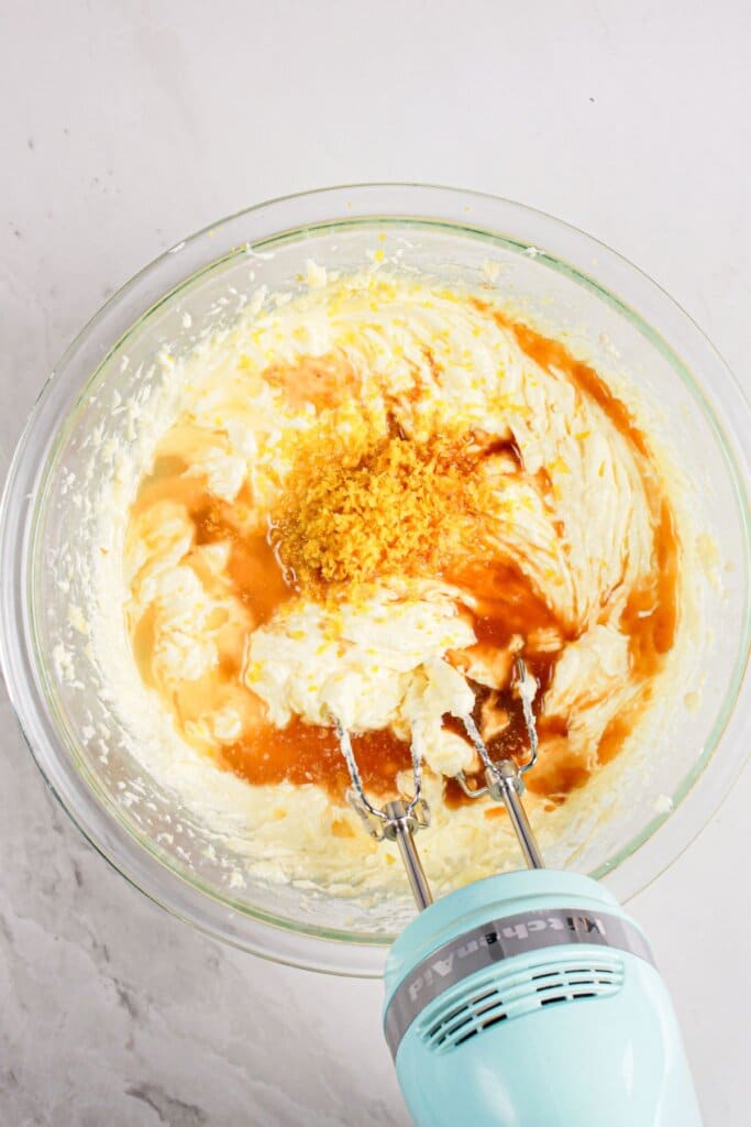 Zest being mixed into batter in a glass bowl.