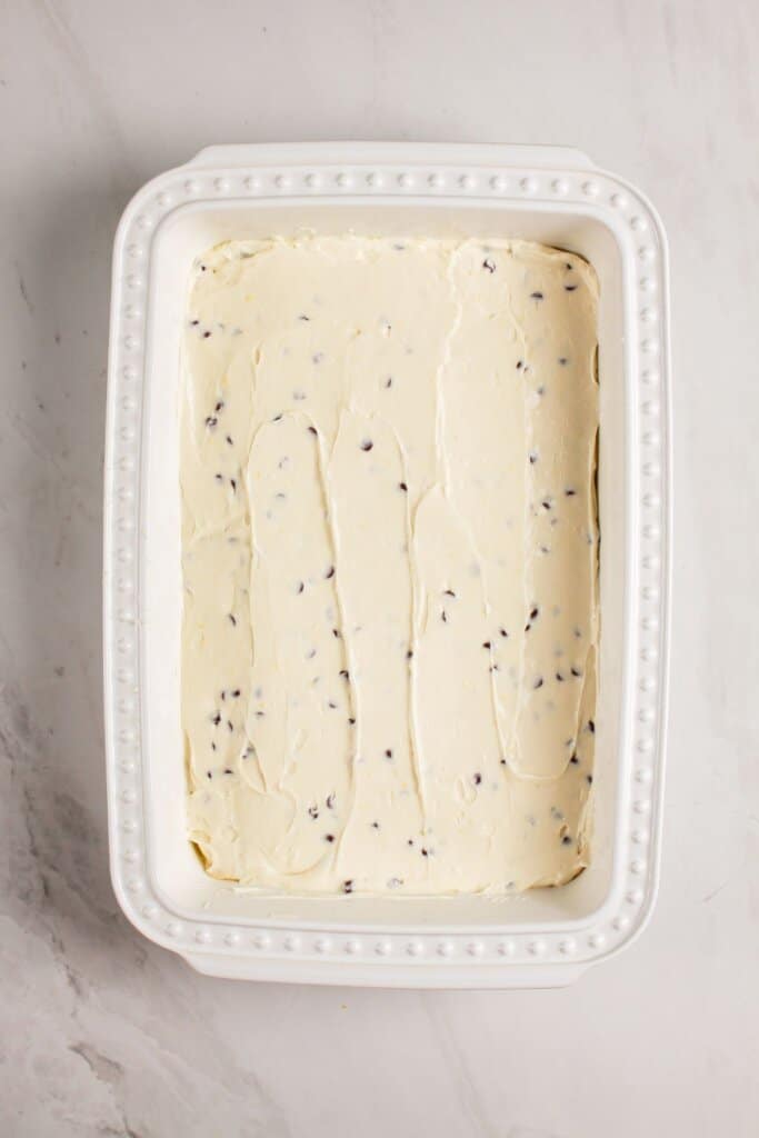 Chocolate chip cream cheese filling being spread on top of dessert.