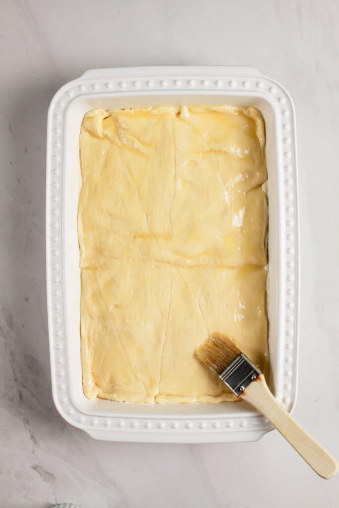 Melted butter being brushed on top of dessert.