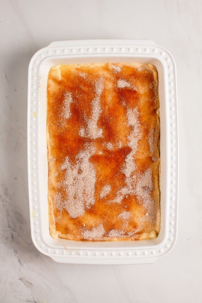 Cinnamon sugar being sprinkled on top of dessert.