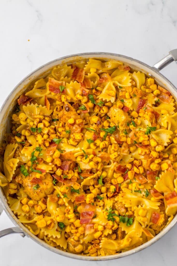 Chicken and corn pasta in a large skillet.