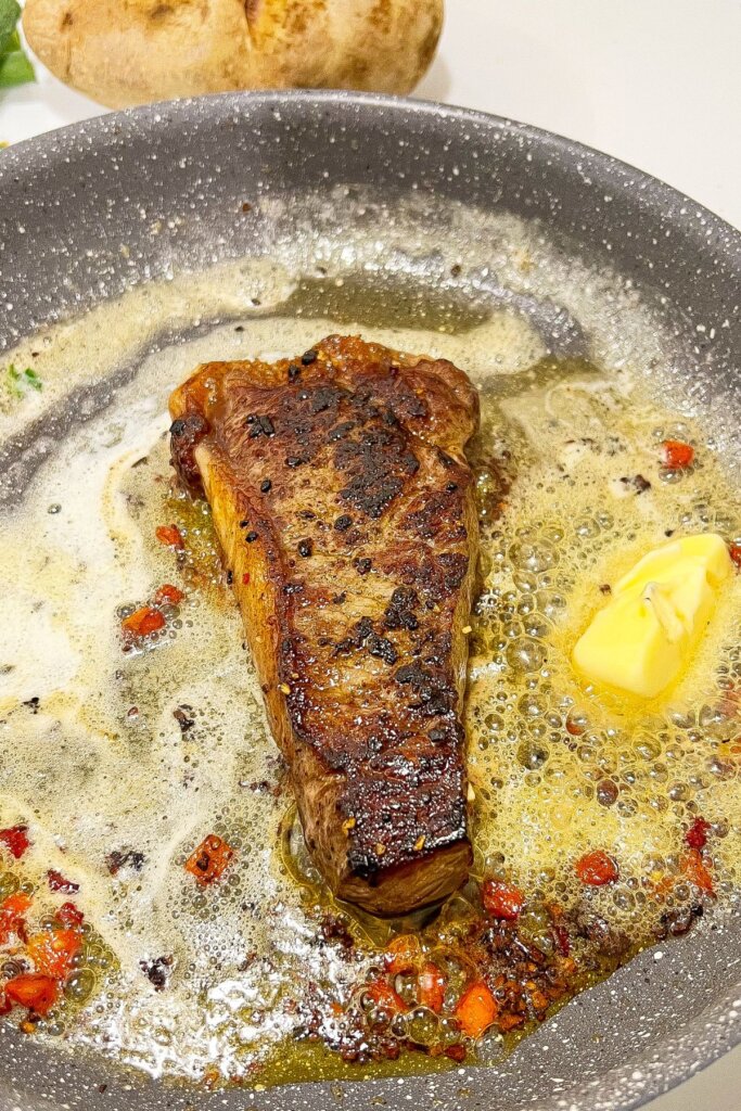 Meat being seared in a skillet.