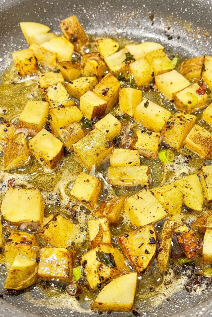 Diced vegetables cooking in a skillet.