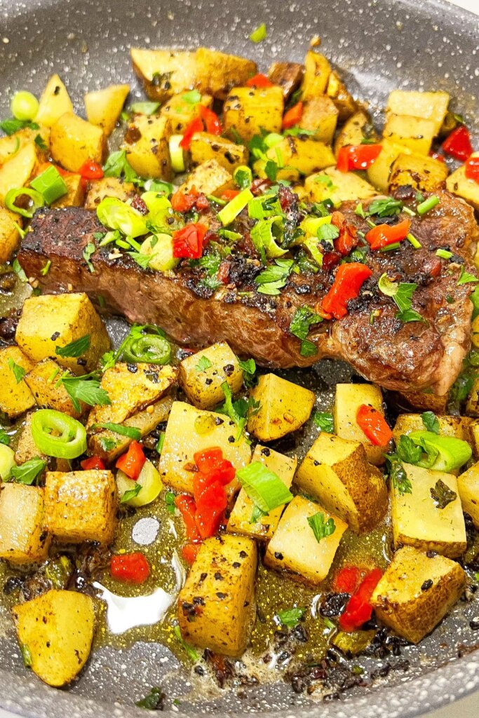 Steak and potatoes in a skillet.