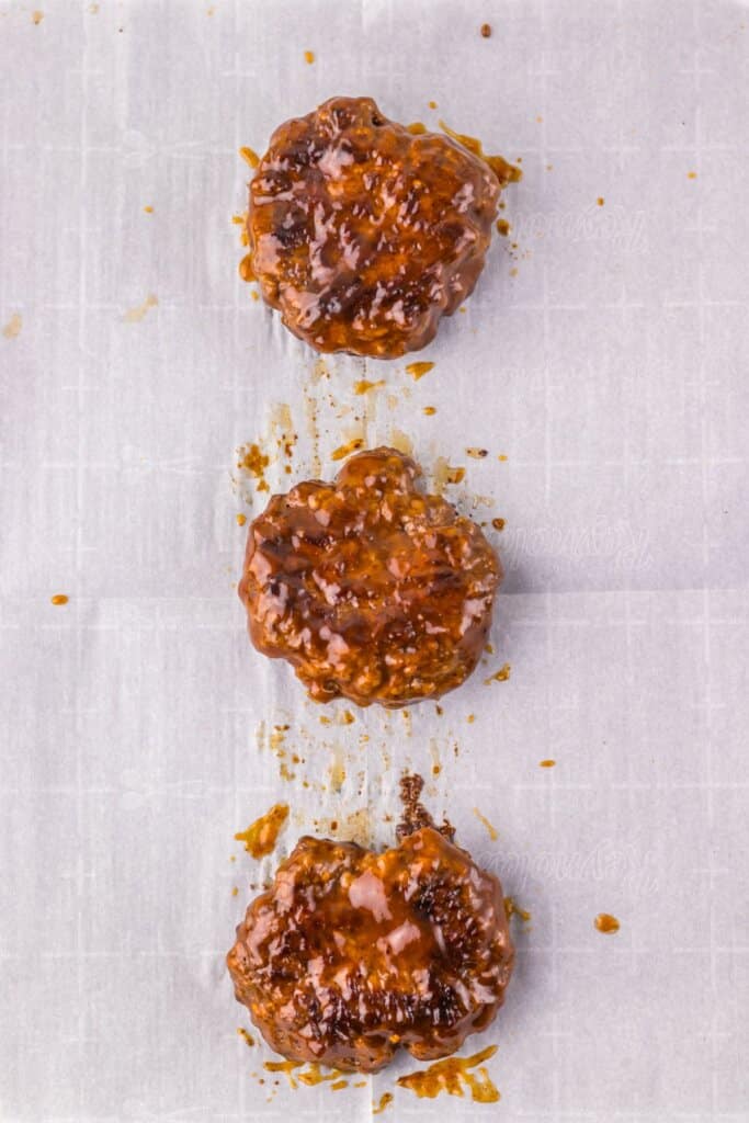 Patties being spread in honey bbq sauce.