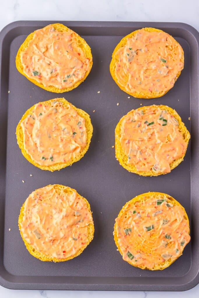 Mayo being spread on buns.