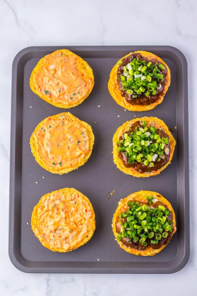 Green onions being added to top of patties.