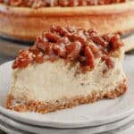 Slice of pecan pie cheesecake on a plate.