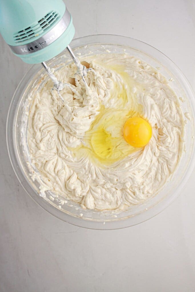 Eggs being mixed into batter in a glass bowl.