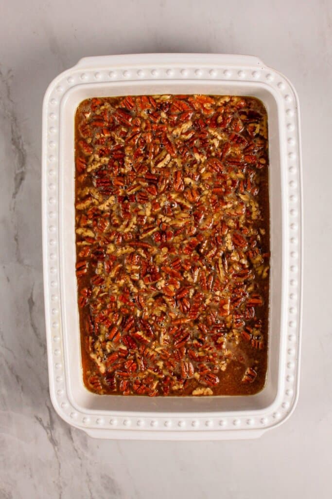 Pecans on top of a dessert in a baking dish.