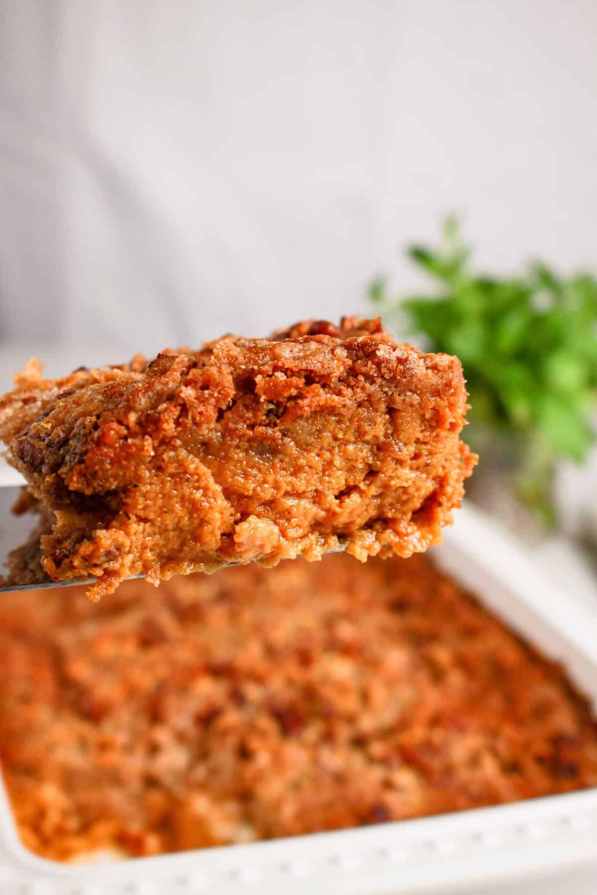 Slice of pumpkin pecan dump cake on a spatula.