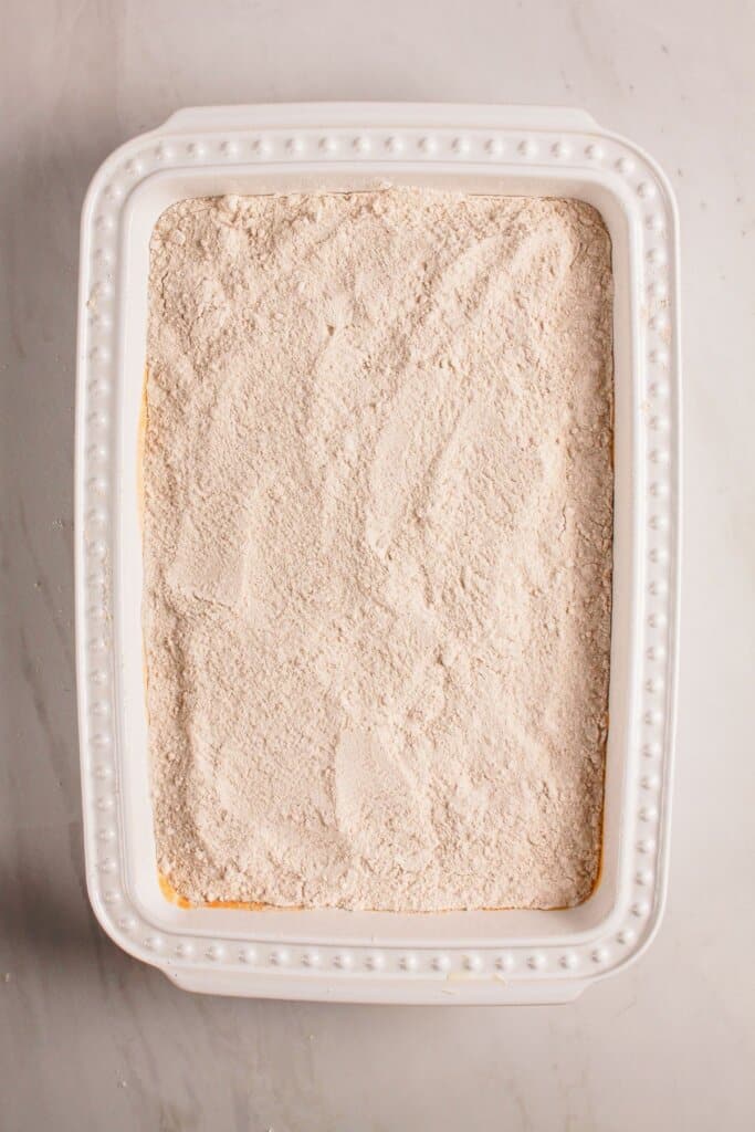 Cake mix spread on top of a dessert in a baking dish.