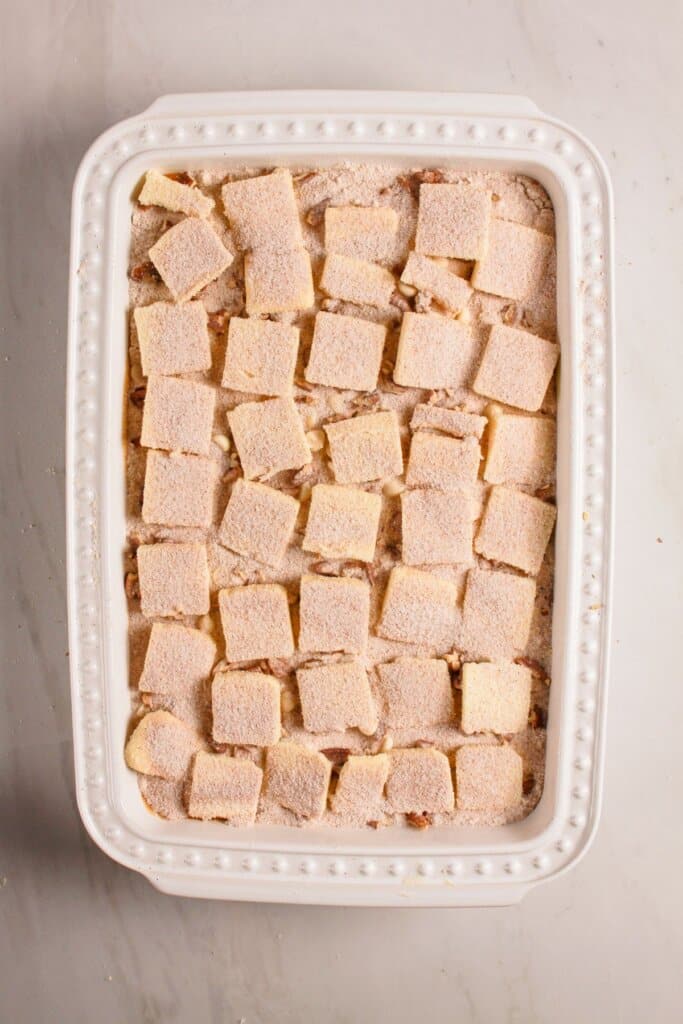 Cinnamon sugar being sprinkled on top of a baking dish.