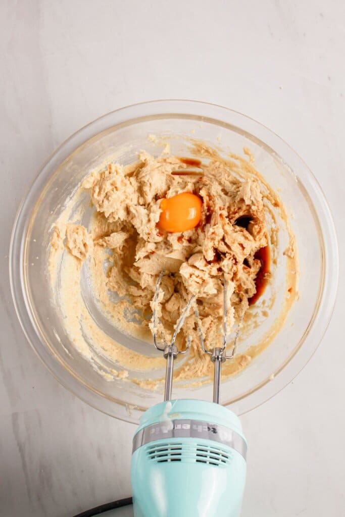 Eggs and wet ingredients being mixed in a glass bowl.