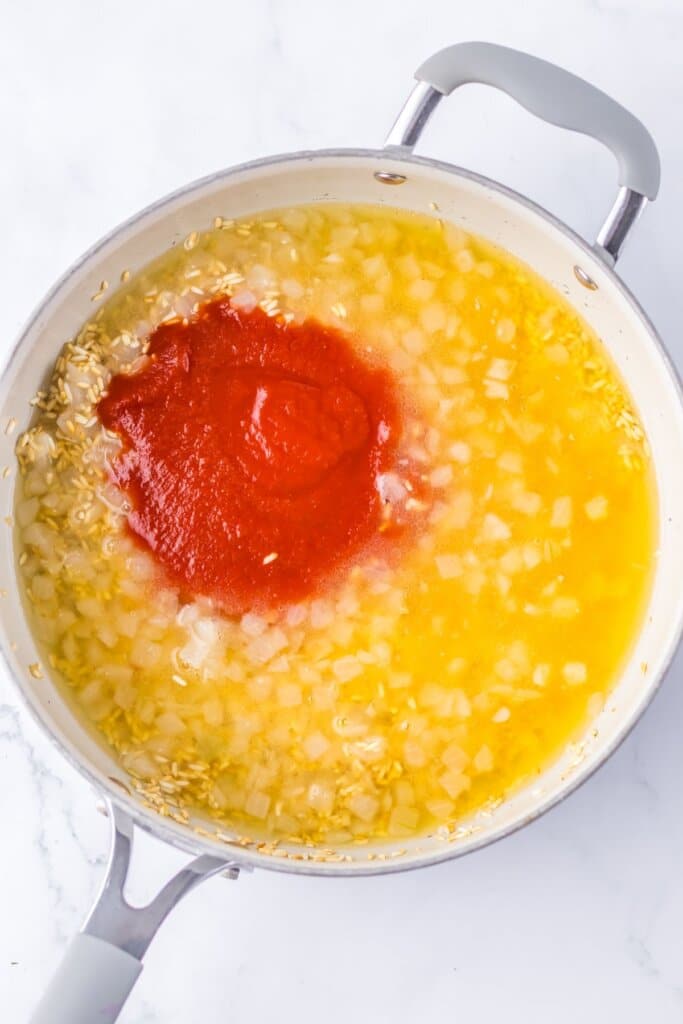 Tomato sauce being added to a skillet.