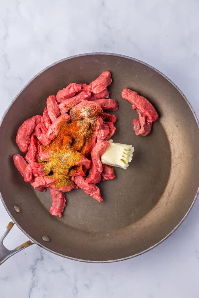 Beef being cooked in a skillet.