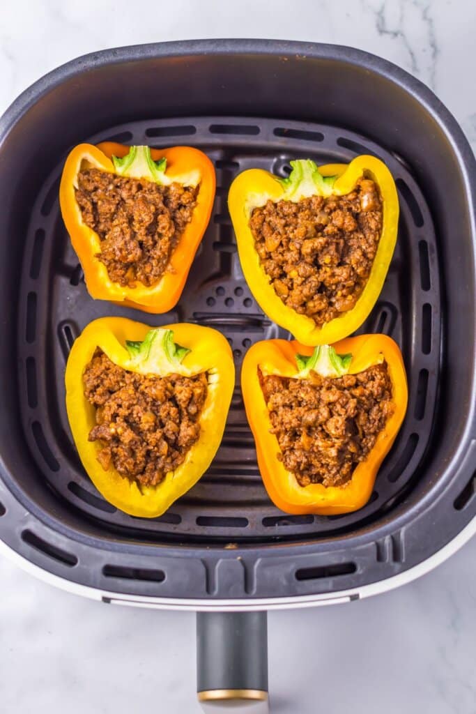 Stuffed peppers in an air fryer basket.