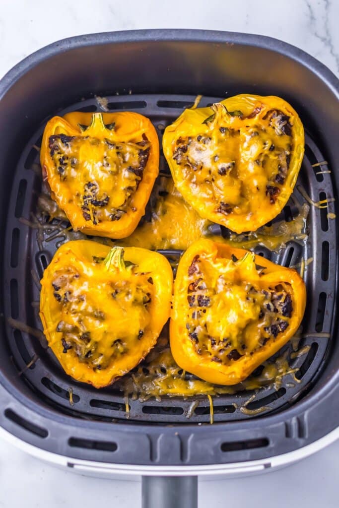 Stuffed peppers in an air fryer basket.