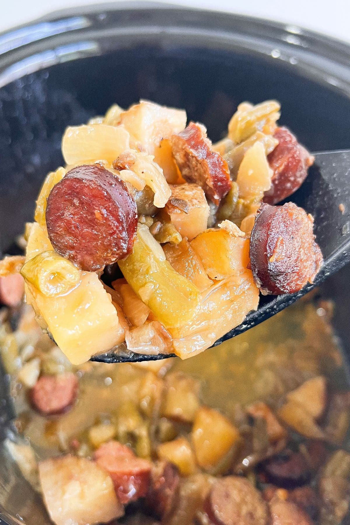Spoonful of meat and vegetables held above the slow cooker.