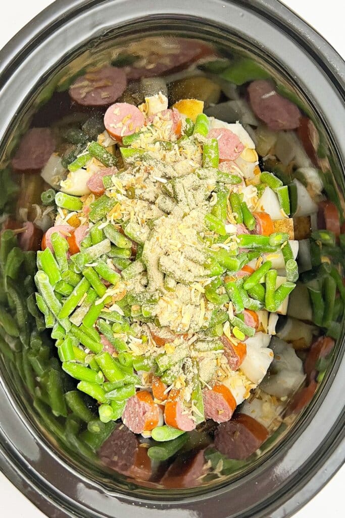 Seasonings, meat and vegetables in a slow cooker.