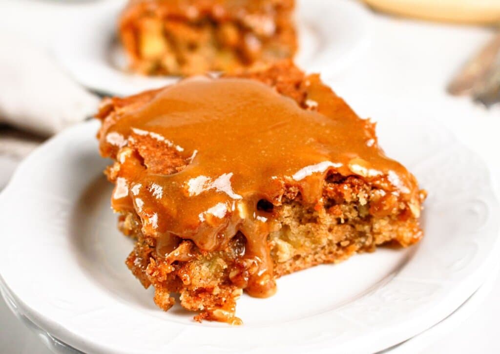 Slice of apple pecan cake on a small plate.
