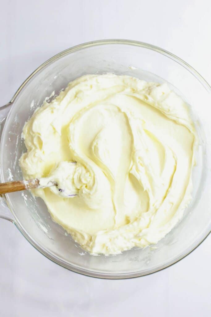 Cream cheese being mixed in a bowl.