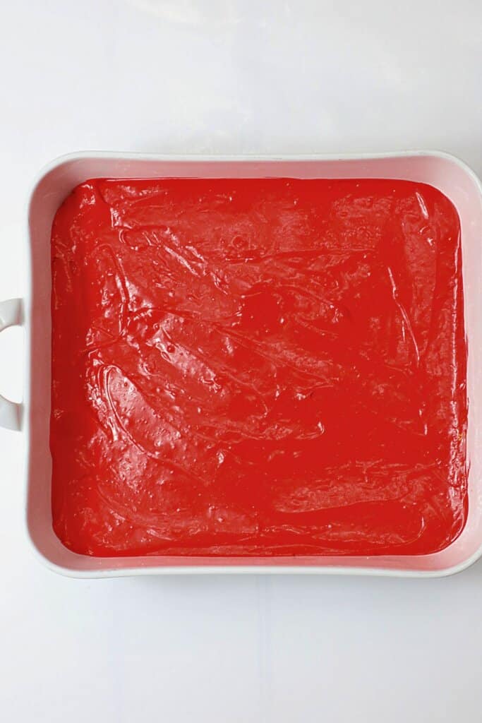 Cheesecake layer being spread on crust.